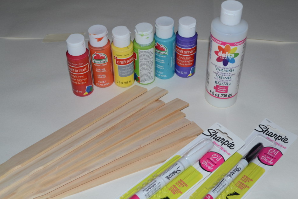 You will need paint stirrers, paint, sealant, paint pens, and paint brushes to make a rainbow of plant markers. 