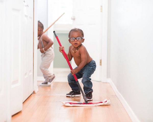 Two little boys cleaning a hallway with a mop