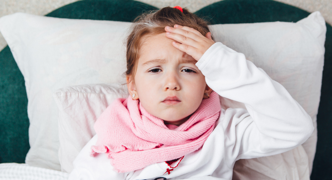 young female child wincing in pain from a fever or sickness